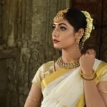 Beautiful Indian woman in traditional saree, adorned with exquisite jewelry, set against historic architecture.