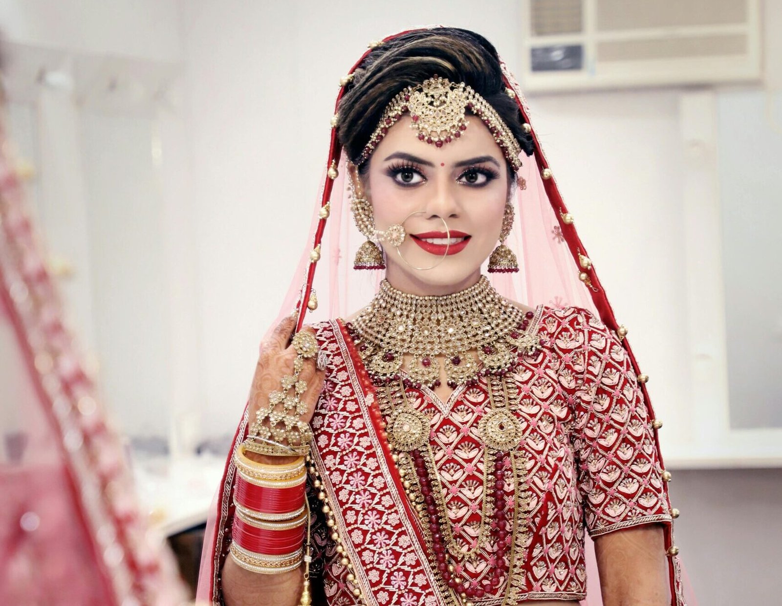 Stunning bride in traditional red and gold wedding attire, captured in a classic portrait style.